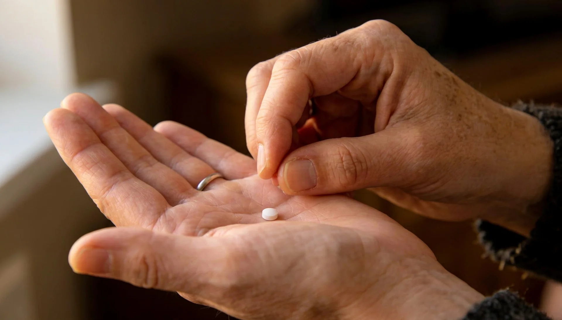 Open hands holding a glass of water with capsules